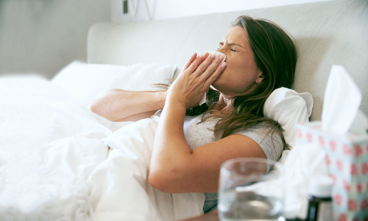 Eine junge Frau hat sich eine Erkältung oder eine Grippe hinzugezogen und liegt nun im Bett