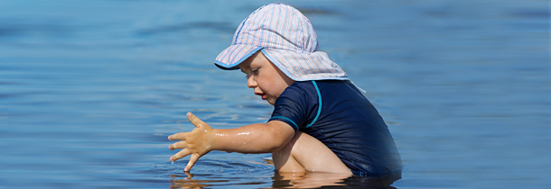 Ein Kleinkind begibt sich mit Sonnenschutz ins Wasser