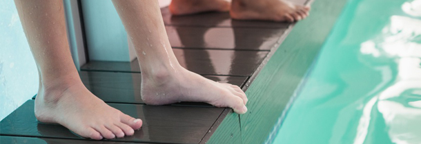 Fusspilz: Die Füsse einer jungen Frau sind unmittelbar am Rand eines Schwimmbads platziert