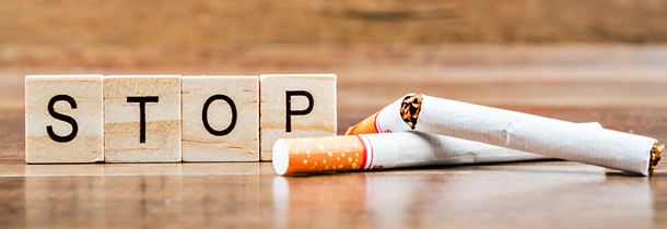 Zigaretten und Blöcke mit der Aufschrift: "STOP" liegen nebeneinander, um das weitere Rauchen zu verhindern
