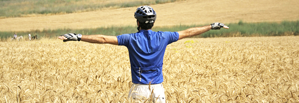 Ein Radfahrer geniesst die angenehme Luft auf einem Weizenfeld trotz Pollenallergie