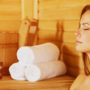 Eine Frau sitzt in der Sauna und geniesst die wohltuende Wärme.