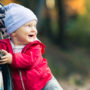 Glückliches Baby im Wald mit Kinderwagen bei einer Wanderung
