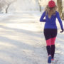 Eine junge Frau mit blonden Haaren joggt im Schnee um die Festtagspfunde abzunehmen