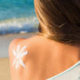 Sonnencreme wird auf einer Schulter in Form einer kleinen Sonne angebracht
